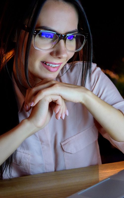 young smiling caucasian businesswoman in glasses looking at laptop
